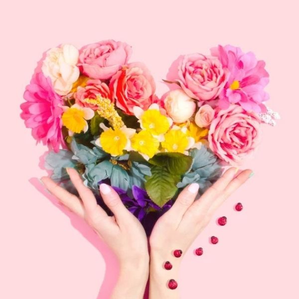 Herz aus Blumen und zwei Händen die es halten